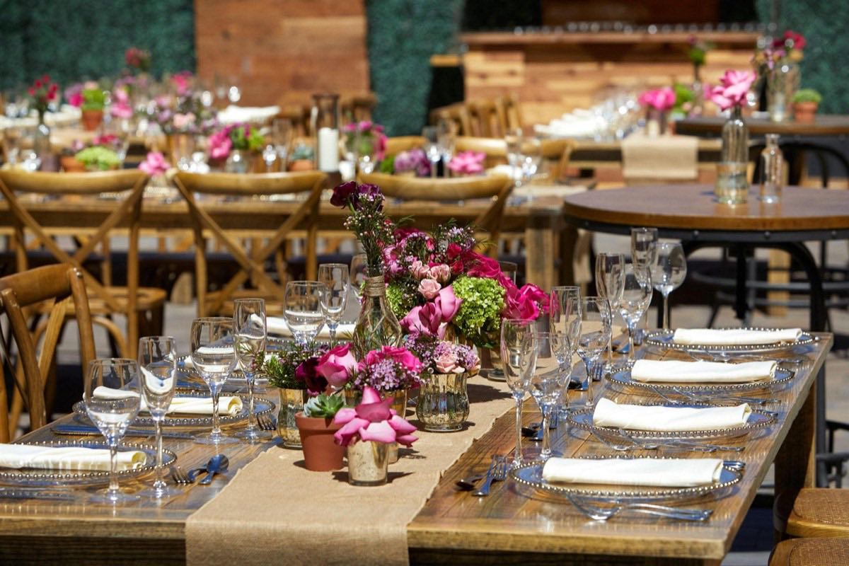 Outdoor luncheon tables with pink florals and wood-cross chairs